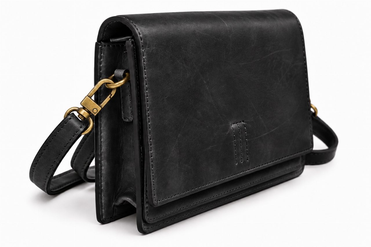Zwarte leren Bag2Bag Nuuk schoudertas met overslag en metalen bandbevestiging.