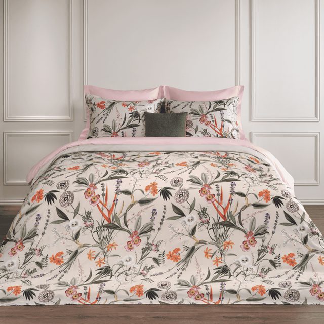 Bed opgemaakt met Dommelin Silvestre met een bloemen- en bladerdessin op een lichte ondergrond.